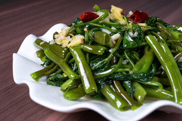 Fried water spinach on a white plate on the table