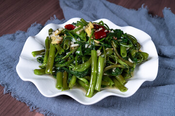 Fried water spinach on a white plate on the table