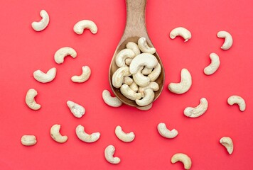 Top View of Cashew Nuts in a Wooden Spoon Isolated on Red Background with Copy Space, Healthy Eating Dry Fruit