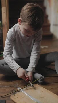 Child engaged in creative crafting activity at home on a wooden floor