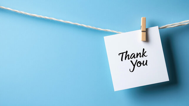 White card with "Thank You" clipped to string against blue background