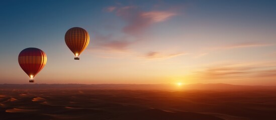 Obraz premium Two colorful hot air balloons drift peacefully against a stunning sunset, creating a serene and picturesque aerial scene.