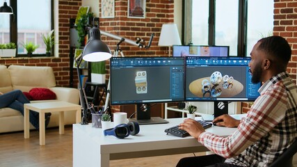 African american industrial designer works on prototypes in a creative studio. Doing tech driven remote work with 3D modeling and CAD software, industrial tools for technical precision. Camera A.