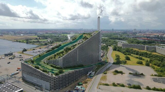 Aerial view highlighting Copenhill, or Amager Bakke, a Copenhagen waste-to-energy plant merging sustainability with leisure activities like skiing, hiking, and climbing establishing drone shot