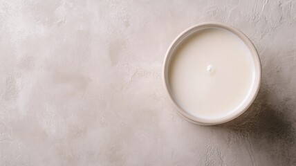 Round bowl of yogurt on textured light surface