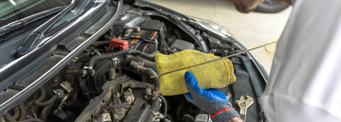 Close up car mechanic checking oil level in auto repair and maintenance service shop, banner size