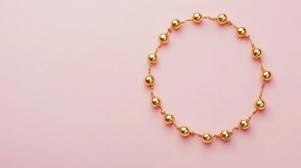 A delicate gold anklet with small bells on a blush pink background
