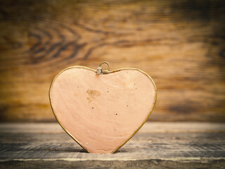 Fototapeta premium Close up of a red metal heart on a rustic wooden table with space for text