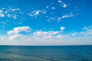 Obraz premium Blue sky with clouds over the sea. Calm landscape on the theme of travel and seaside recreation.