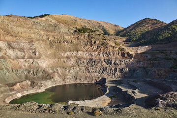 Old open mining pit in mountain. Open-pit quarry, mine landscape, pond. Historical travel destination place Ak-Tyuz, Kyrgyzstan. Abandoned Kyrgyz mining and metallurgical plant. lead mining, deposit