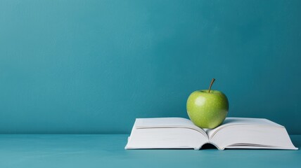 Educational and curriculum concept. Open book with a green apple on top, set against a teal background.