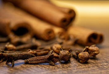 Cinnamon sticks and a pile of dried cloves close up.