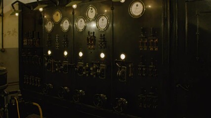 An old, industrial control panel with a variety of gauges, switches, and dials. Industrial  elements in the interior of Fort de Mutzig fortress, now a museum.