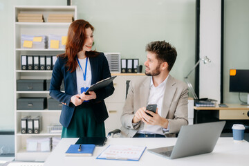 Two business workers talking on the smartphone and using laptop