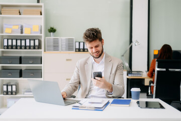 Fototapeta premium Young businessman working with working notepad, tablet and laptop documents talking on the smartphone