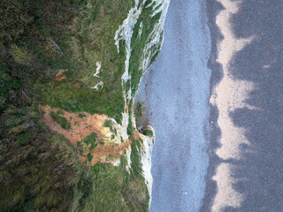 vue aérienne prise par un drone montrant les falaises en Normandie, la plage de galets et la mer,...