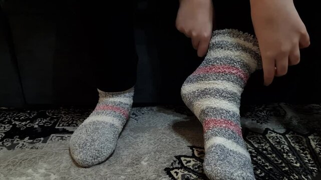 Girl putting warm socks at home. Heating season concept