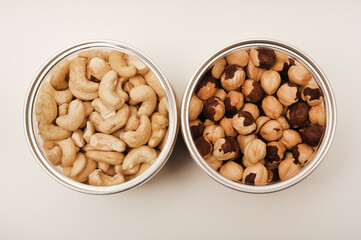 Cashews and hazelnuts in a jar on a white background.