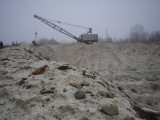 Large metal excavator on tracks. Career. Sand mining. Bad weather.