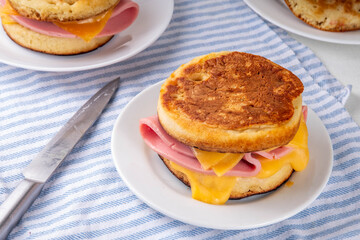 Breakfast crumpet sandwich, british pancake scones burger with cheese and ham, on kitchen table, with stack of crumpets and butter