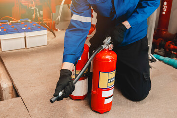 Engineer checks fire extinguisher in fire control room to ensure safety. When an emergency occurs