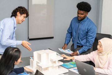 Architects engineers collaborating on building design project in modern office, diverse team of professionals female muslim architect and male engineers discussing architectural model of structure