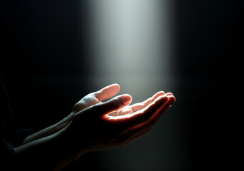 Open hands receiving light in dark environment, symbolizing spirituality, hope, and divine connection
