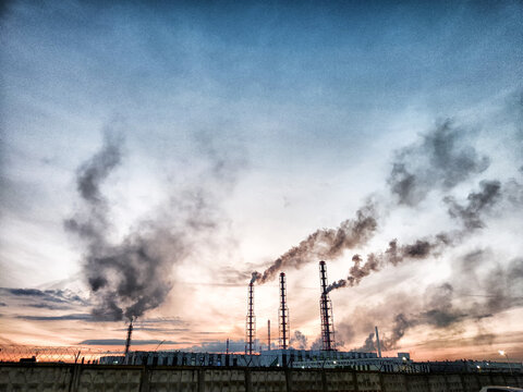 Heavy smoke billows from industrial pipes at sunset, showcasing environmental pollution and its impact on the skyline