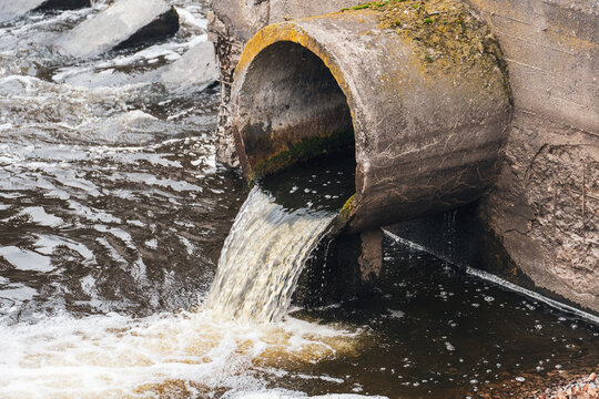 Dirty water flows from the pipe into the river, environmental pollution. Sewerage, treatment facilities