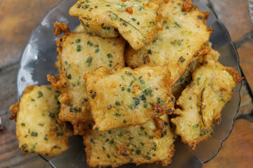 Serving of fried tempeh flour or mendoan cooked in yellowish color on a blue glass plate, photo taken flat lay with a varnished wood background