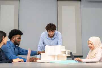 Architects engineers collaborating on building design project in modern office, diverse team of professionals female muslim architect and male engineers discussing architectural model of structure