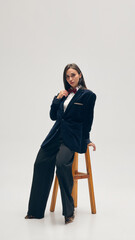 Full-length portrait of confident young woman wears velvet blazer, bow tie, pants and white shirt...