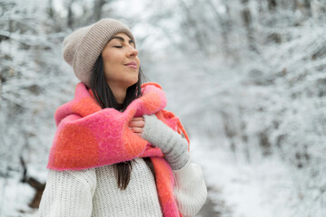 Beautiful  woman breathing fresh air in a snowy forest. Winter time