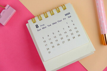 Monthly desk calendar for month 2025 on an office pink background. 