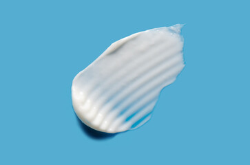 A sample of white cosmetic moisturizer on a blue background