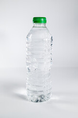 Plastic bottle filled with water with green cap on white background. Concept: Water, consumables, food and drink.