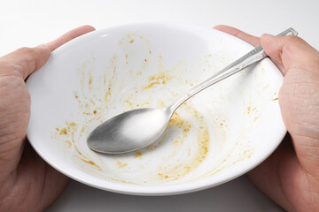 Empty dish plate with traces and pieces of food. Finished White bowl with Spoon and Fork. Isolated on white background