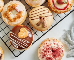 Donuts, sweet cakes, desserts, assorted, toppings, chocolate, strawberries, cream, sprinkles, wire rack, white background, delicious food, sweet food, desserts, culinary. 