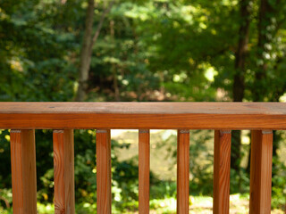 Wooden deck railing with lush green forest backdrop. Perfect for relaxation and outdoor living.