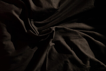 Dark fabric texture. Draped cloth with deep shadows and subtle light creating a dramatic effect.