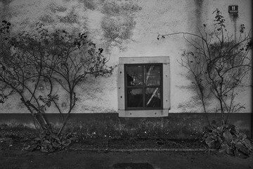 A strange old poor square window on an old peeling wall. B/W