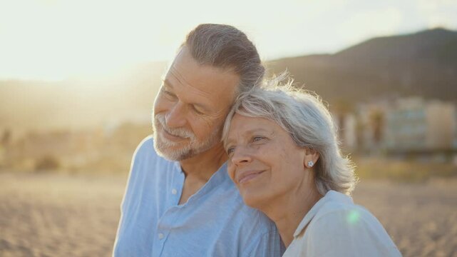 Beautiful happy senior couple dating at the seaside during summertime - Mature married couple in love bonding outdoors at the beach, concepts about elderly lifestyle, relationship and quality of life

