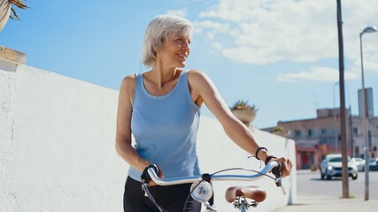 Beautiful happy senior woman cycling during summertime - Mature adult female with gray hair riding bicycle, concepts about elderly lifestyle, transportation and quality of life	 - Powered by Adobe