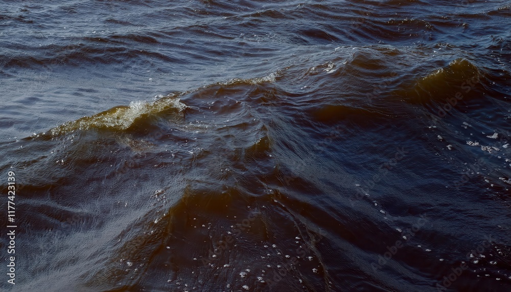 Poster close-up view of gentle brownish waves with sparkling droplets on windy water surface, capturing nat