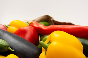 Colorful fresh vegetables including tomatoes, peppers, avocado, eggplant and cucumbers on white background. Top view. Healthy eating. Copy space