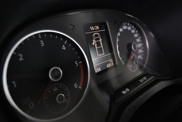 Close up of a car's dashboard showing the speedometer tachometer and digital display