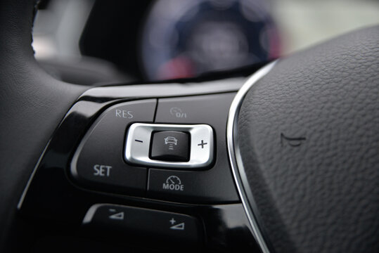 Close up of a car's steering wheel controls featuring buttons for cruise control mode selection and settings adjustments