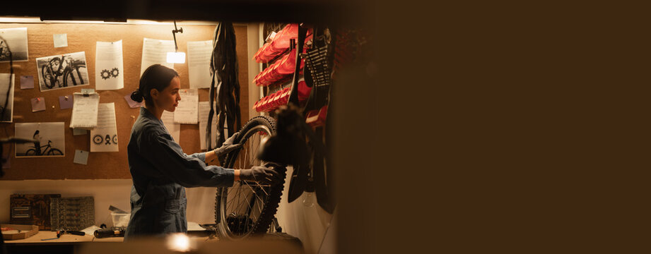 Young woman repairing bicycle wheel in workshop