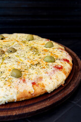 pizza recien horneada con queso y aceitunas en fondo negro