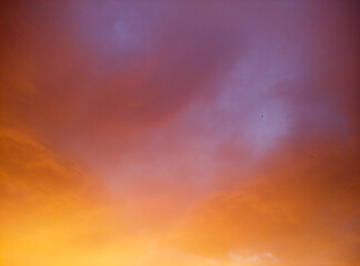 Vibrant sky with orange, pink, and purple gradient during sunset. Abstract nature background of colorful evening clouds